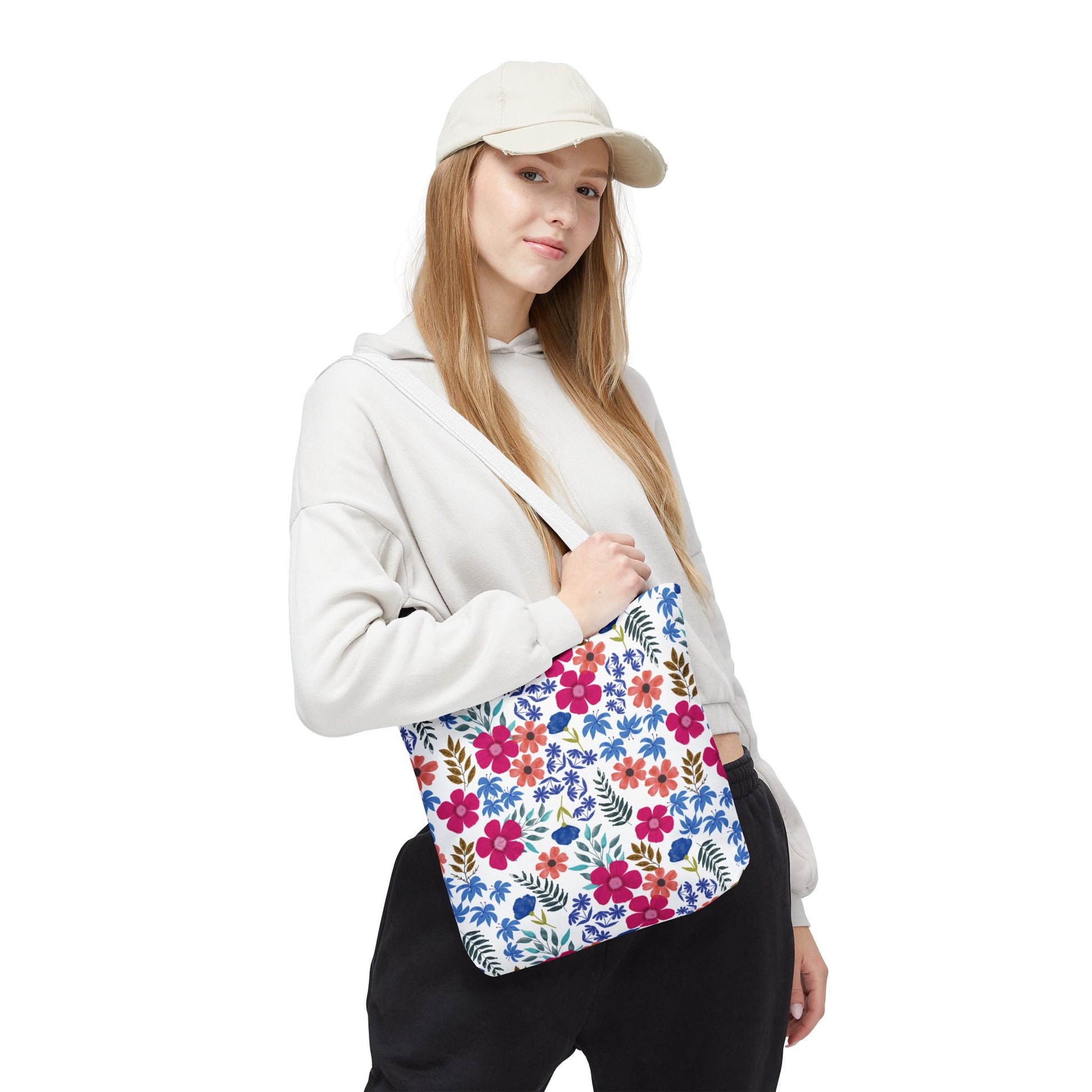 Young person wearing a light hoodie and baseball cap, carrying a vibrant Floral Tote Bag with an all-over floral print, ideal for joyful summer outings, showcasing FireBrook Designs' stylish, uplifting essentials.