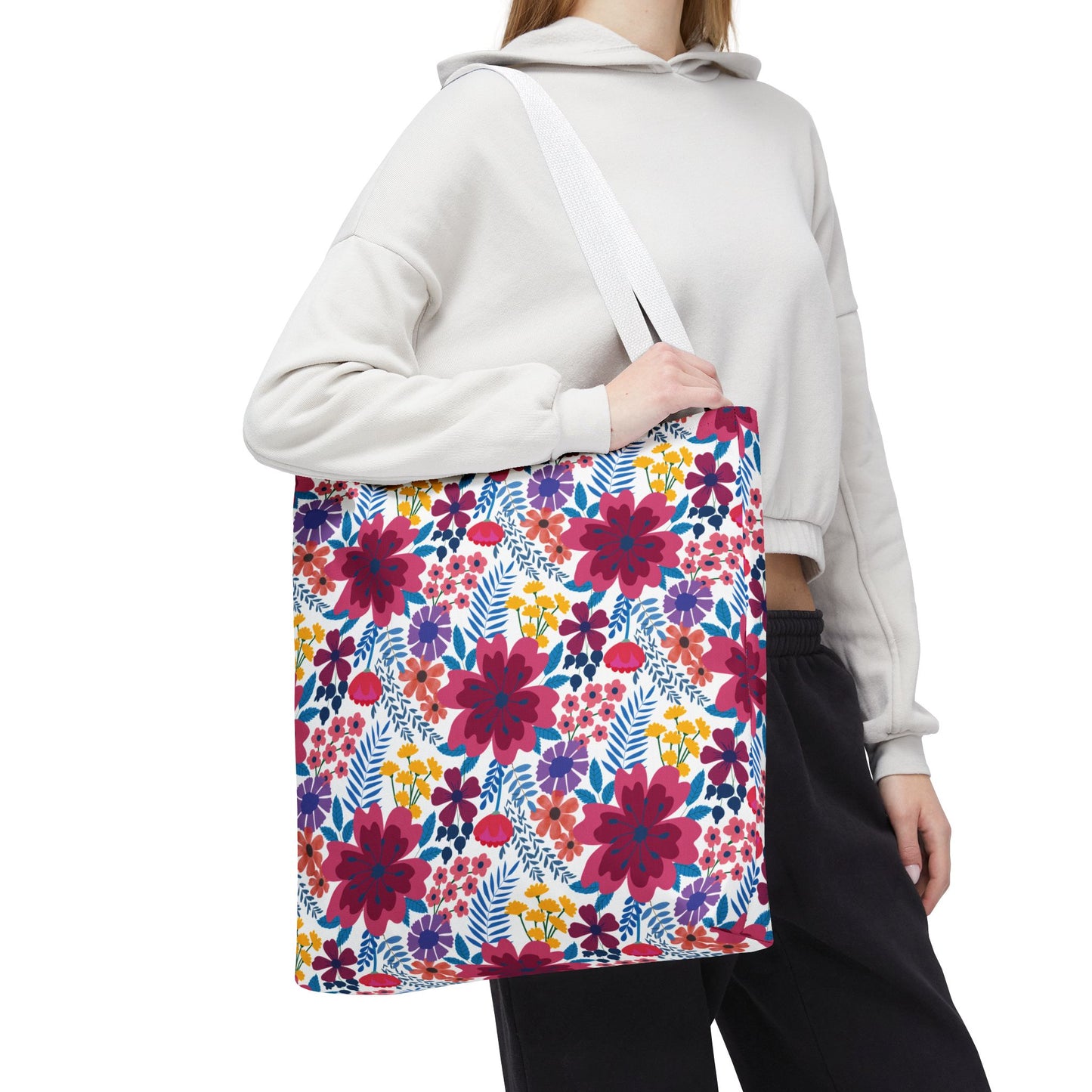Floral Tote Bag with vibrant magenta, red, and purple blooms, complemented by yellow and blue accents, carried by a person in a gray hoodie. Ideal for uplifting summer outings.