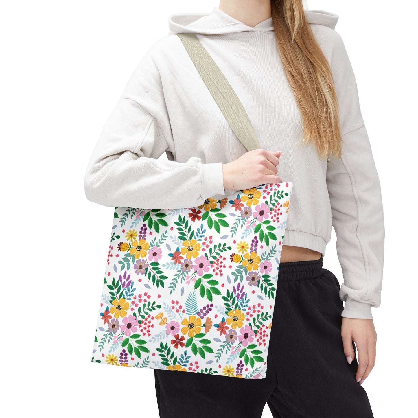 Floral Tote Bag featuring a vibrant, colorful floral pattern on a white background, carried over the shoulder by a person wearing a light-colored cropped hoodie, ideal for joyful summer outings.