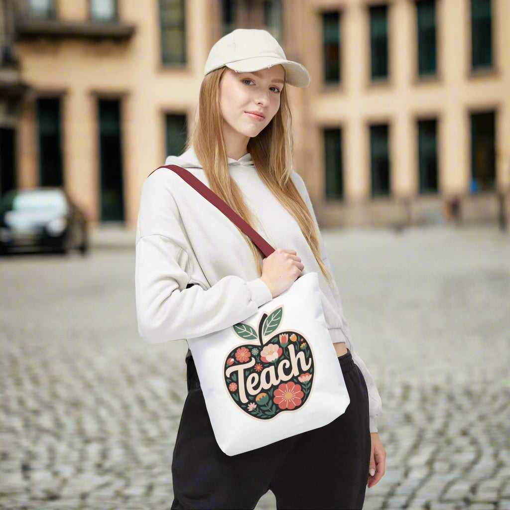 Floral Apple Tote Bag - Hand-Drawn Pastel-Colored Design with 'TEACH': A cheerful, apple-shaped tote adorned with pastel floral illustrations, ideal for educators and nature lovers, featuring durable polyester and reinforced handles.