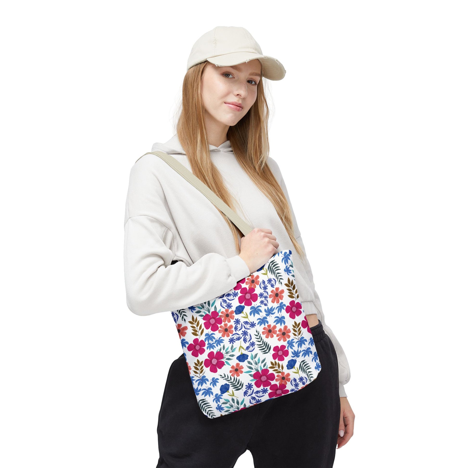 Person in light-colored hoodie and beige cap holds the Confetti Wildflower Tote Bag featuring vibrant floral patterns, ideal for summer outings, reflecting FireBrook Designs' commitment to joyful, stylish essentials.