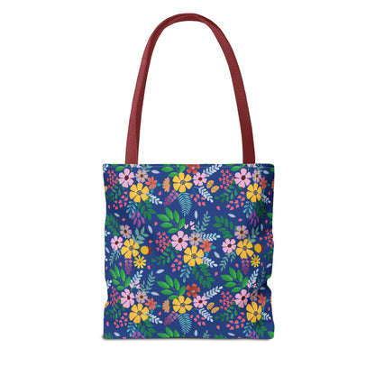 Floral Tote Bag featuring vibrant yellow, pink, orange, and purple blossoms with green and blue foliage on a deep-blue background; maroon straps complete this lively, durable accessory perfect for joyful summer outings.