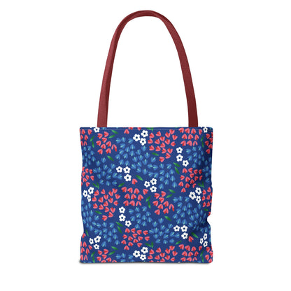 Berry Blue Festival Tote Bag features a deep blue body adorned with white blossoms and colorful leaf-shaped petals, complemented by burgundy-red straps. Ideal for summer outings, blending style and functionality.