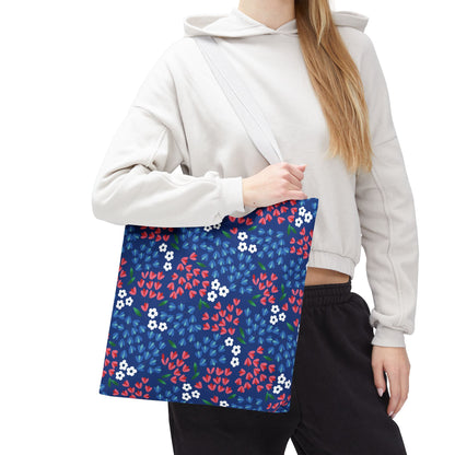 Person carrying the Berry Blue Festival Tote Bag with a navy background and vibrant floral pattern, ideal for joyful summer outings. The casual attire enhances the bag's cheerful and versatile appeal.