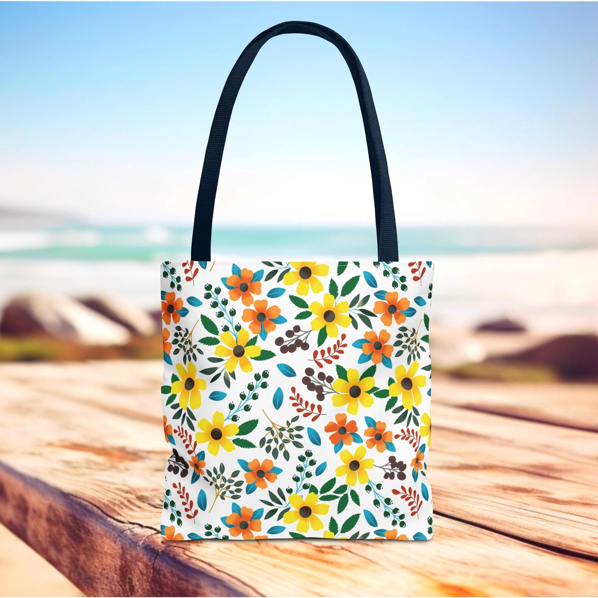 Floral Tote Bag with bright floral prints on a white background, standing upright on a wooden surface. Featuring long, dark handles, this stylish bag embodies FireBrook Essentials' cheerful design perfect for summer outings.