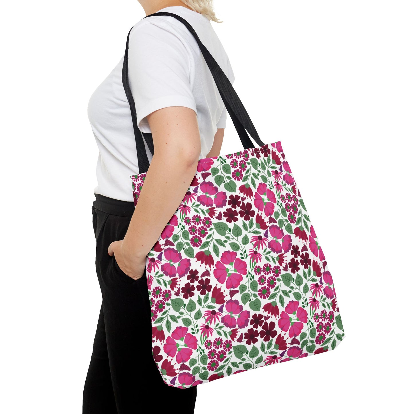 The Pink Lady Tote Bag showcases a vibrant floral print, featuring black straps and a durable canvas body, ideal for adding a cheerful touch to casual outfits and daily errands.