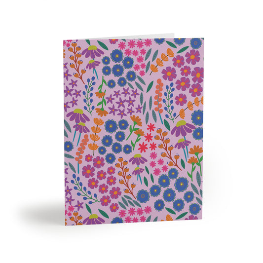 Floral Greeting Cards — Pack of 8/16/24, featuring a vibrant, stylized floral pattern on a lavender background, shown standing upright. Ideal for sending thoughtful messages, each card includes a matching white envelope.