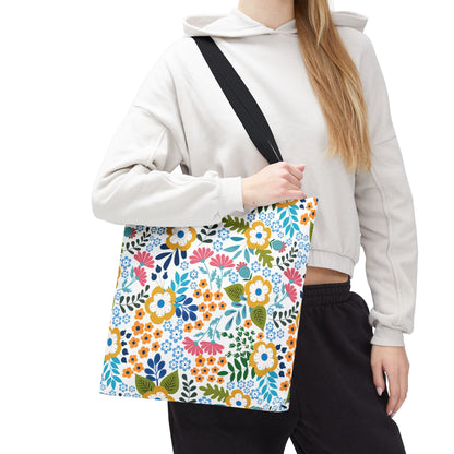 Floral Tote Bag with vibrant floral design, held by a model in casual loungewear. Perfect for summer outings, the bag features reinforced black straps and a durable, spacious polyester body.