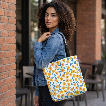 Young woman with curly hair wearing a blue denim jacket carries the Buttercup Cream Tote Bag, featuring a yellow floral pattern. The bag's cheerful design complements summer outings, reflecting FireBrook Designs' uplifting style.