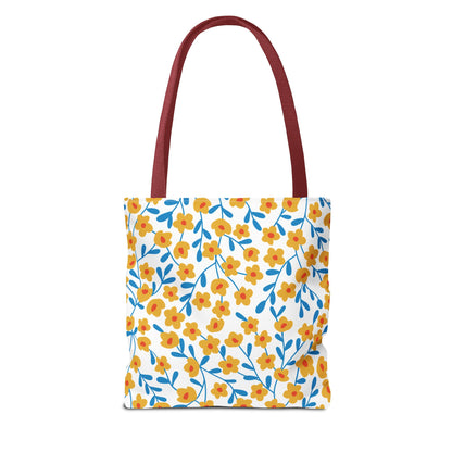 Buttercup Cream Tote Bag featuring small yellow flowers with red centers and blue stems on a white canvas, with dark-red handles, perfect for brightening summer outings.