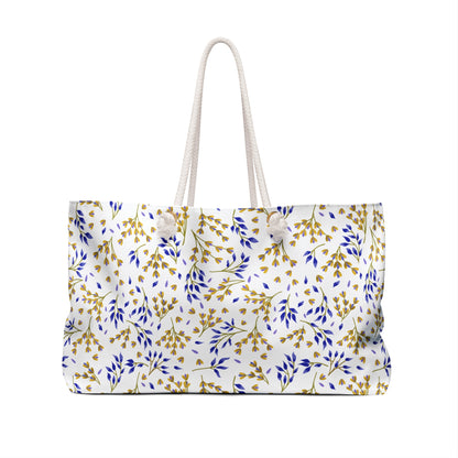 Weekender Bag with thick white rope handles, featuring a white fabric adorned with gold and blue leafy sprigs, perfect for stylish travel, offering spacious storage and a luxurious cream interior.