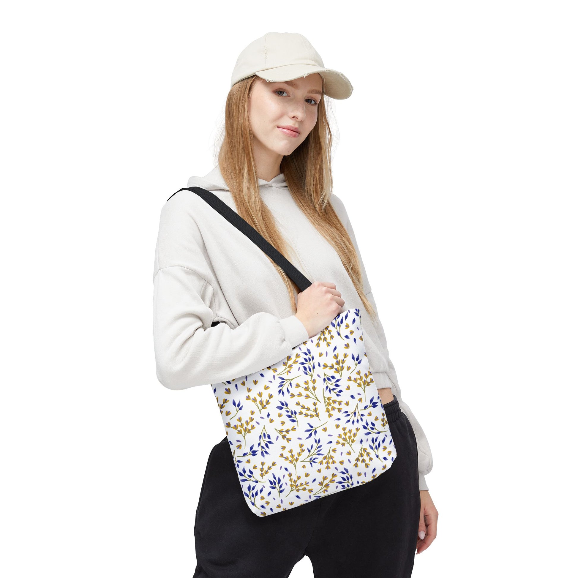 Floral Tote Bag with a blue-and-gold leafy pattern on a white background, worn by a casually dressed young person. Ideal for summer outings, reflecting FireBrook Designs' uplifting and joyful style.