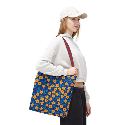 Cobalt Poppy Field Tote Bag: Young woman in casual attire carries a deep blue tote adorned with yellow-orange flowers, perfect for summer outings. Features durable polyester body, reinforced handles, and boxed corners for extra room.