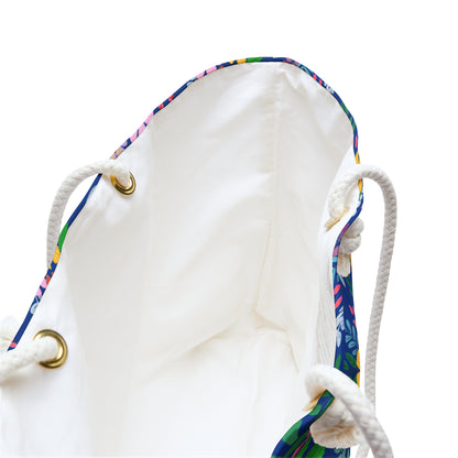 Weekender Bag with an off-white interior, colorful floral-patterned trim, and thick braided rope handles threaded through brass-tone grommets, ideal for stylish travel and spacious storage.