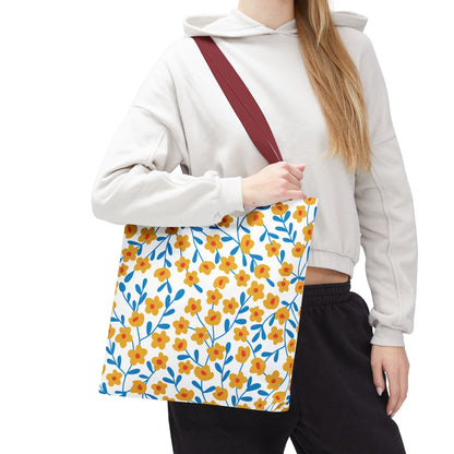 Buttercup Cream Tote Bag features a vibrant pattern of yellow-orange flowers with blue stems, set against a white background, complemented by a wide dark red strap, ideal for brightening summer outings.