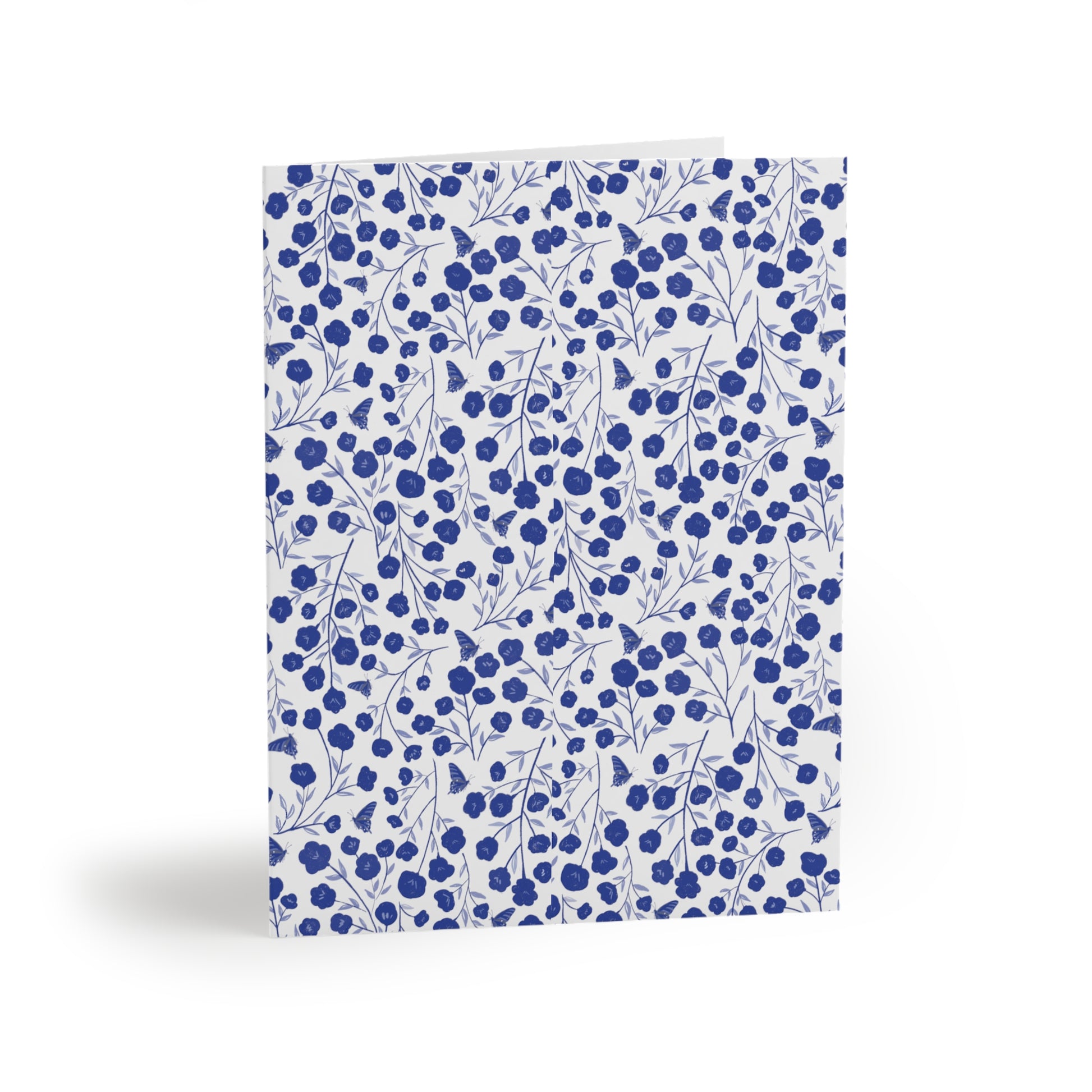 Floral Greeting Cards — Pack of 8/16/24 features a dense pattern of blue flowers and butterfly silhouettes on a white matte background, folded upright, embodying FireBrook Designs' uplifting and joyful style.