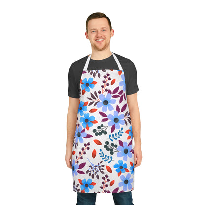 Smiling young man in a black t-shirt and jeans models the FireBrook Designs Floral Apron, featuring vibrant blue, purple, and red flowers. Ideal for cooking and hosting, emphasizing comfort and style.
