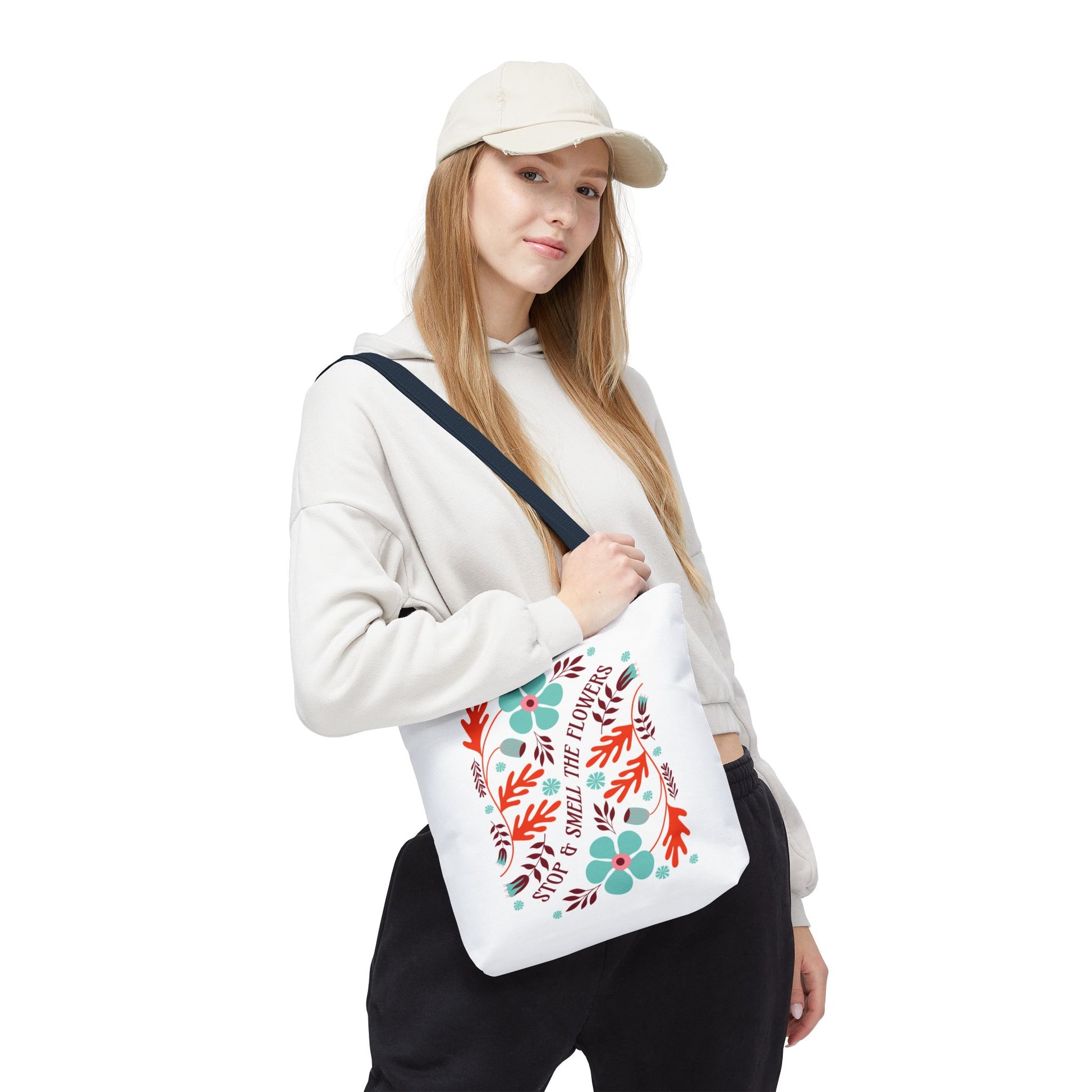 Woman in a hat holding the Stop and Smell The Flowers Tote Bag, featuring a floral design, embodying tranquility and nature-inspired beauty.