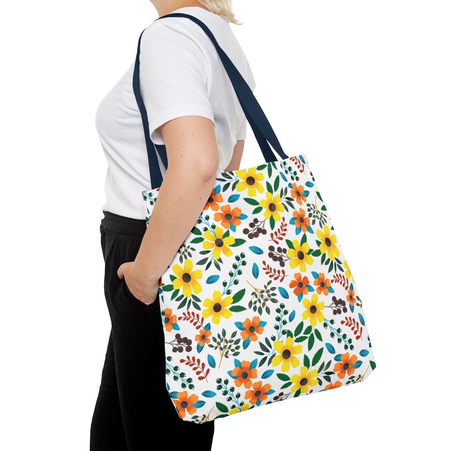A person carries the Floral Tote Bag, featuring bright yellow and orange flowers, green leaves, and navy straps, ideal for summer outings and cheerful style, over their shoulder.
