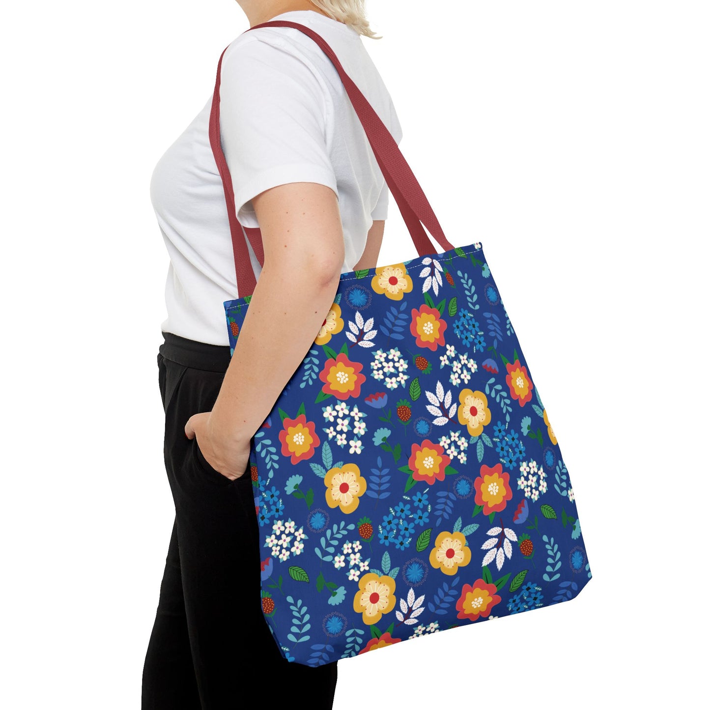 Cornflower Patch Tote Bag in vibrant floral print and reddish-brown straps, showcased over the shoulder of a person wearing a plain white T-shirt and black pants, embodying FireBrook Designs' cheerful, joyful style.