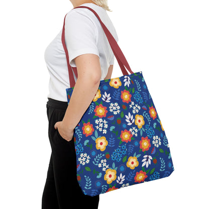 Cornflower Patch Tote Bag in vibrant floral print and reddish-brown straps, showcased over the shoulder of a person wearing a plain white T-shirt and black pants, embodying FireBrook Designs' cheerful, joyful style.