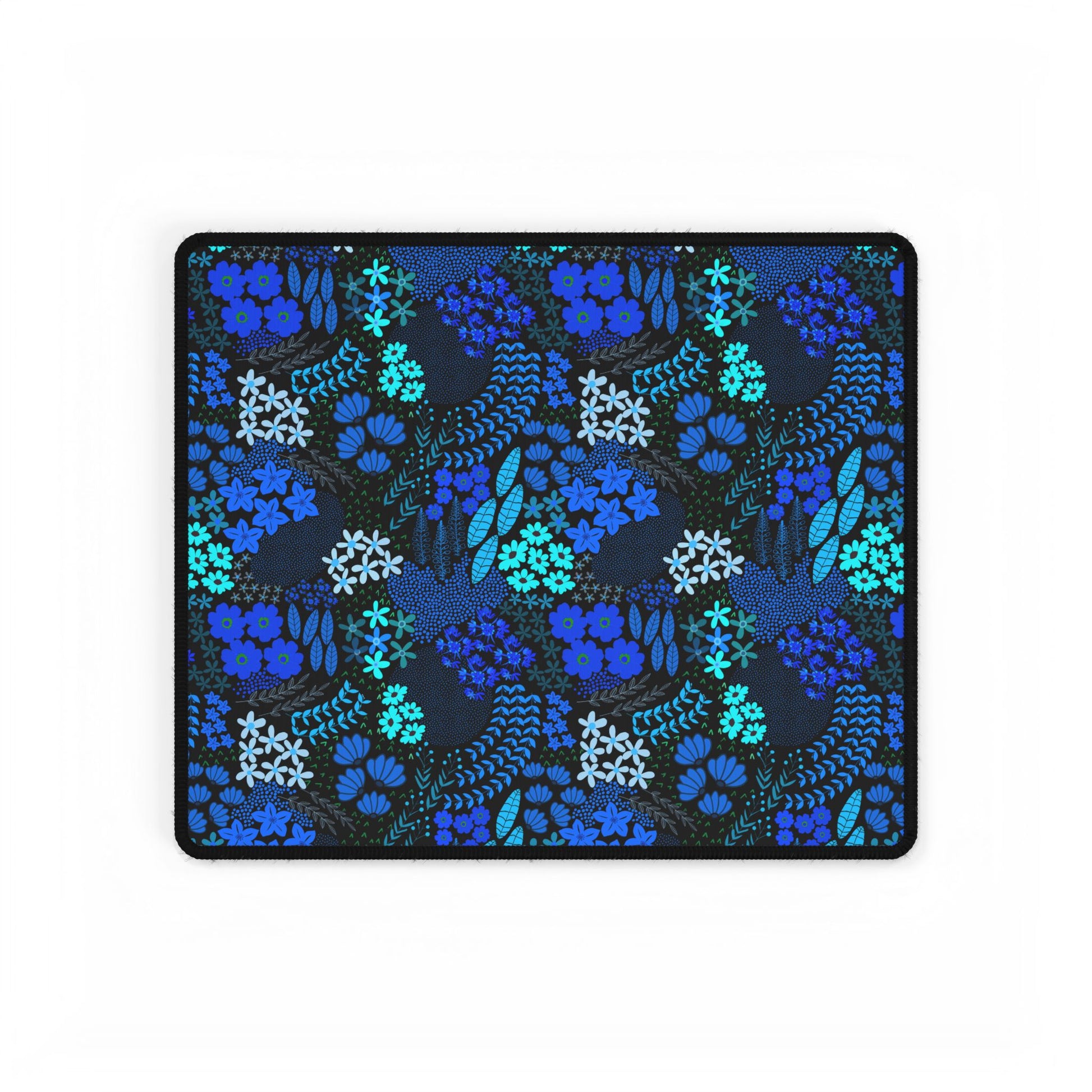 Blue Floral Desk Mat featuring a dark background with hand-drawn blue and teal botanical patterns, edged with a stitched black border. Ideal for adding elegance and style to your workspace.