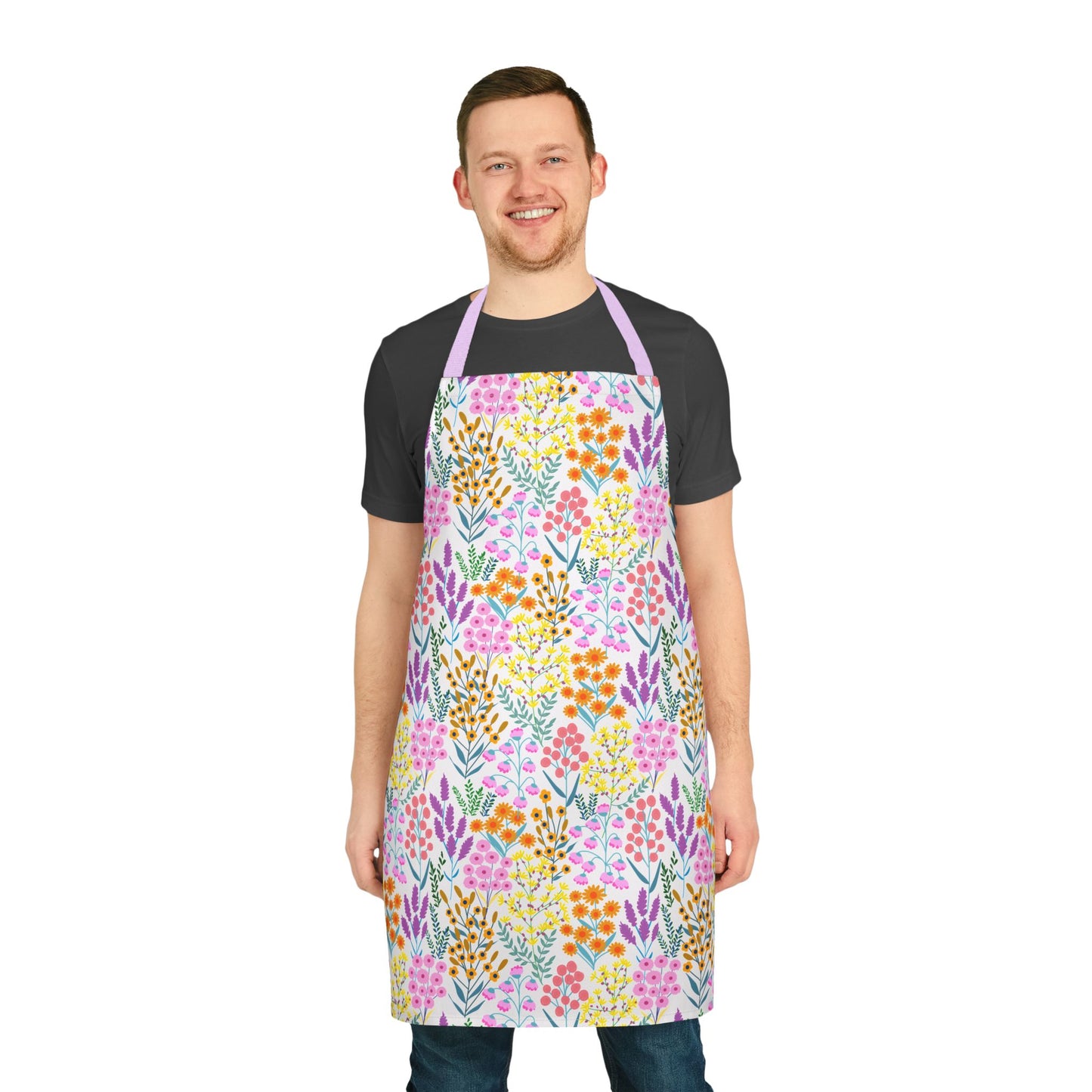Smiling young man models FireBrook Designs' Floral Apron, showcasing vibrant blossoms on a stain-free, comfortable polyester canvas with a lavender neck strap, perfect for joyful cooking or crafting activities.