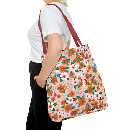 Floral Tote Bag with deep red straps, featuring orange and white blossoms on a pale pink background, carried over the shoulder by a person in casual attire, embodying FireBrook's joyful, stylish essence.
