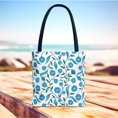 Blue Floral Tote Bag with dark handles, featuring vibrant blue flowers and green leaves on a white background, ideal for summer outings. Perfect blend of durability and cheerful design from FireBrook Designs.