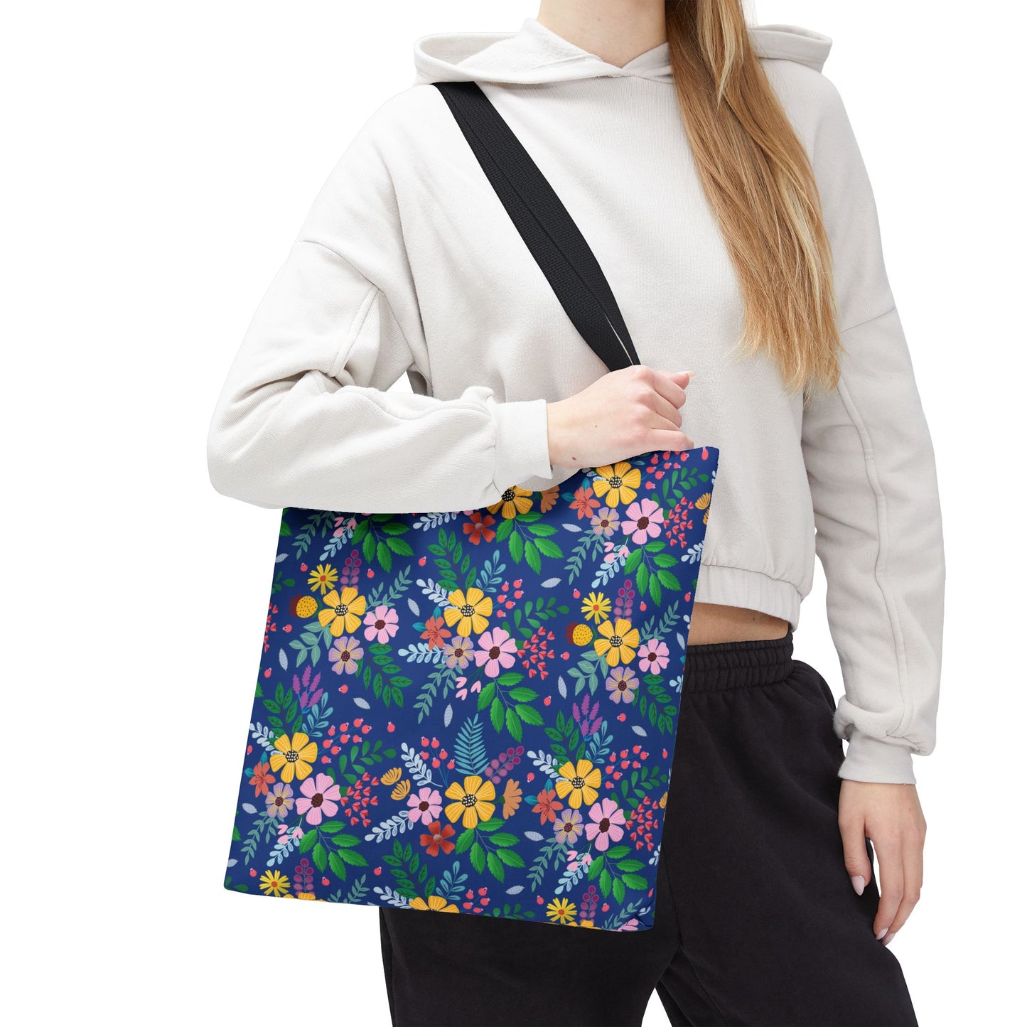 The Deep Sea Floral Patch Tote Bag features vibrant blossoms on a deep blue background, held by a person wearing a light hoodie. Ideal for stylish, cheerful outings, embodying FireBrook Essentials' uplifting design ethos.
