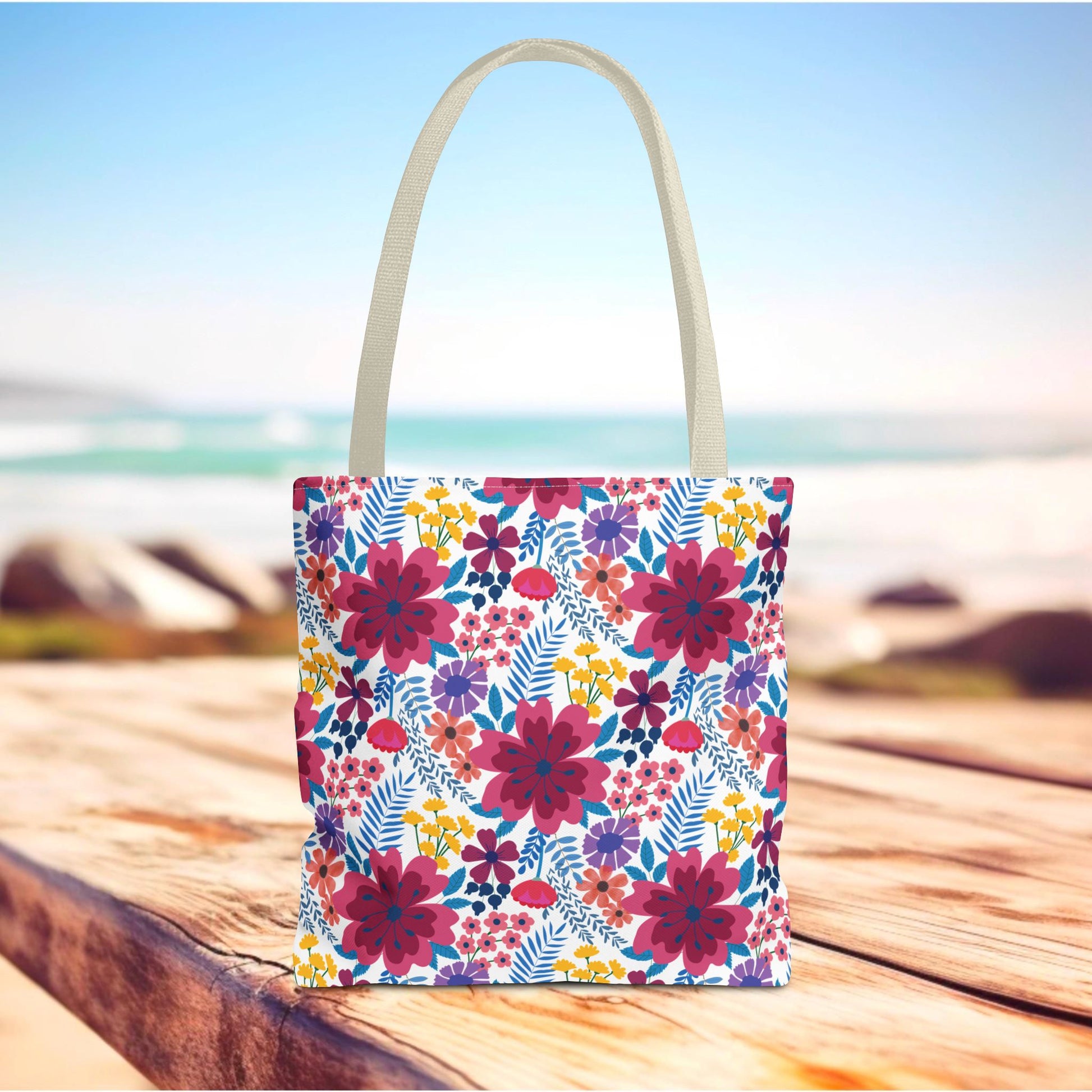 Violet Daisy Carnival Tote Bag on wooden surface, featuring vibrant floral design with magenta, purple, and yellow blooms. Ideal for summer outings, embodying FireBrook Essentials' uplifting, joyful style.