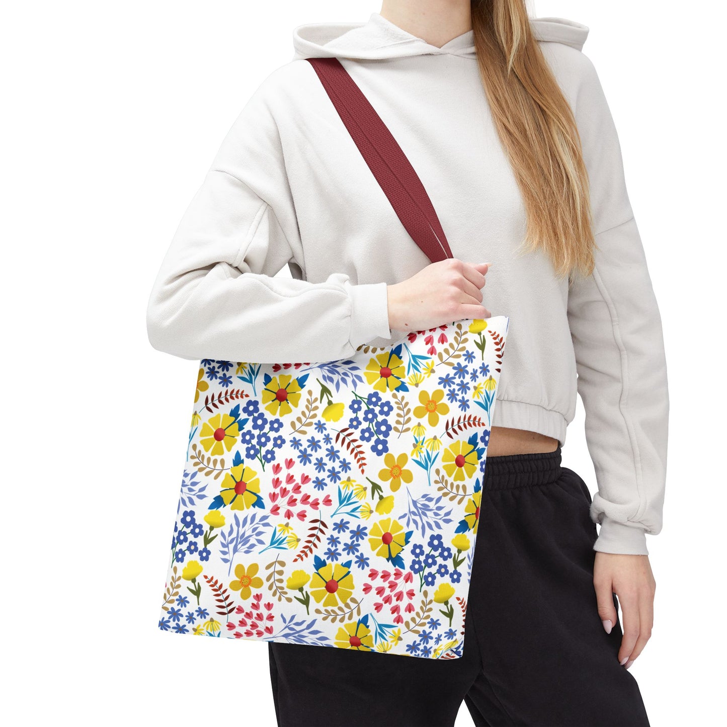 Floral Tote Bag with a vibrant, colorful blossom pattern and burgundy strap, ideal for summer outings. Seen carried by a person in casual attire, showcasing its cheerful design and spaciousness.