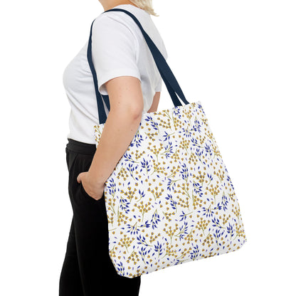 Person wearing plain attire carries the Wild Herb Garden Tote Bag, featuring a white base with blue-and-gold leaf pattern and navy straps, ideal for vibrant summer outings.