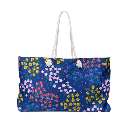 Weekender Bag with navy blue body adorned with colorful floral print and sturdy white rope handles, ideal for stylish travel. Generous size offers ample space, reflecting FireBrook Designs' blend of comfort and joy.