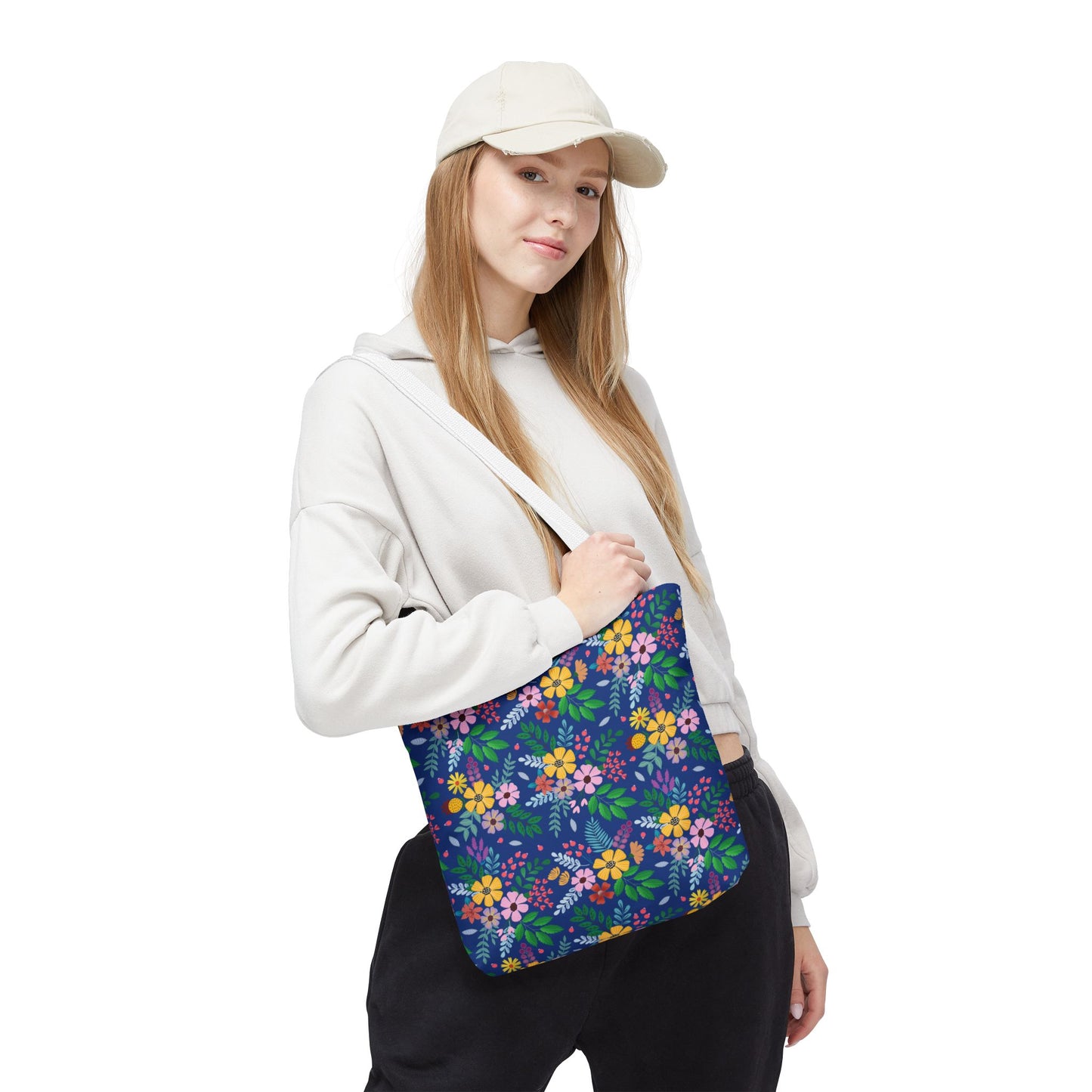 Floral Tote Bag with vibrant blossoms and foliage on dark blue, slung over a young woman's shoulder. Perfect for summer outings, embodying FireBrook Designs' joyful and uplifting style.
