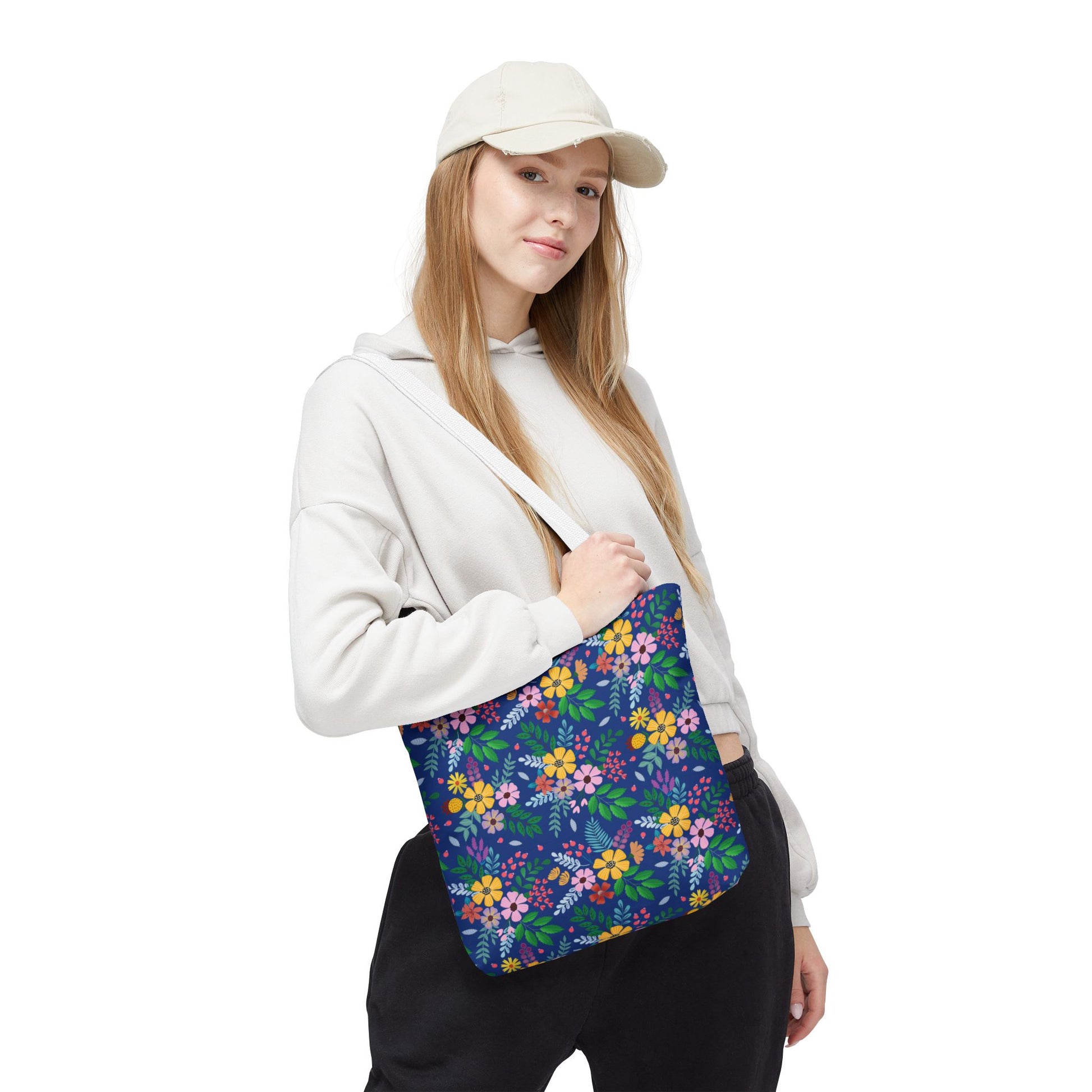 Floral Tote Bag with vibrant blossoms and foliage on dark blue, slung over a young woman's shoulder. Perfect for summer outings, embodying FireBrook Designs' joyful and uplifting style.