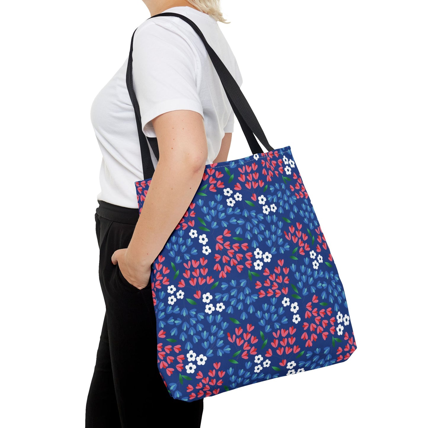 Berry Blue Festival Tote Bag in use, depicting its durable polyester build with a vibrant floral pattern of red, blue, and white flowers. It's perfect for summer outings, showcasing FireBrook Designs' uplifting style.