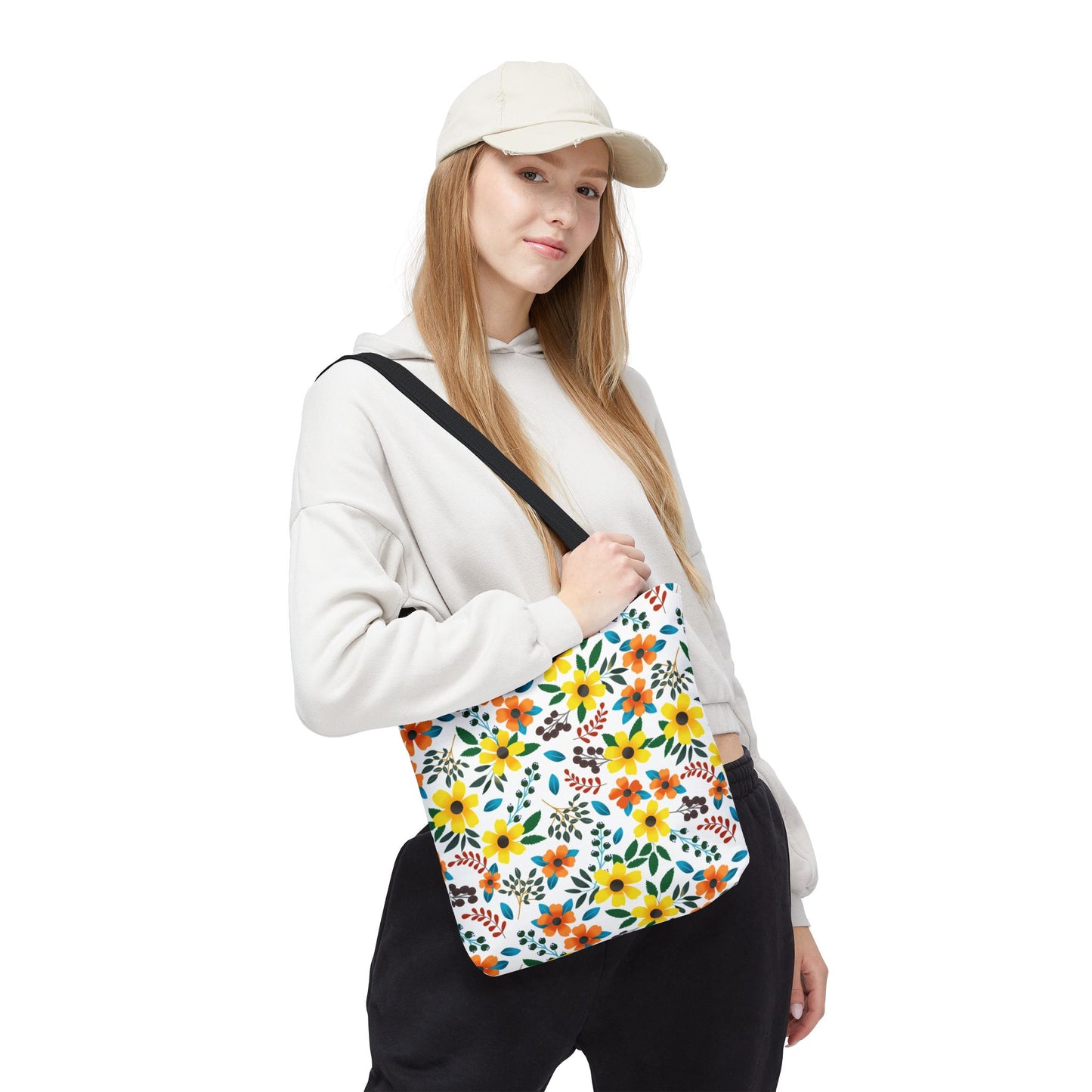 Sunny Meadow Mix Tote Bag with vibrant floral pattern in yellow, orange, green, and blue, worn by a young woman against a white backdrop, embodies FireBrook Designs’ joyful and stylish ethos.