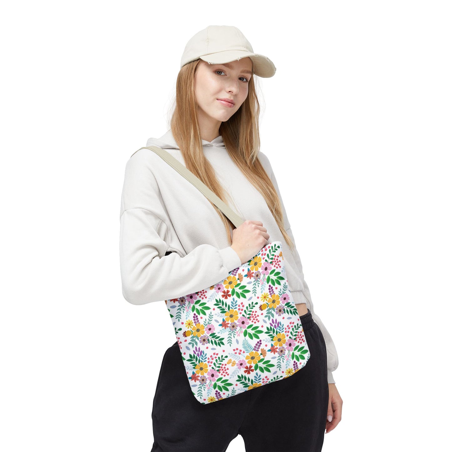 Young woman wearing a light hoodie and beige cap carries the Spring Floral Patch Tote Bag, showcasing its vibrant multicolored floral pattern, ideal for joyful, stylish outings.