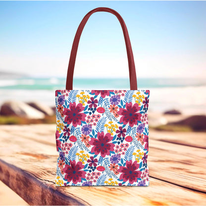 Violet Daisy Carnival Tote Bag on a wooden surface with a beach backdrop, showcasing a vibrant floral pattern and reddish-brown handles, embodying FireBrook Designs' cheerful and uplifting style ideal for summer outings.