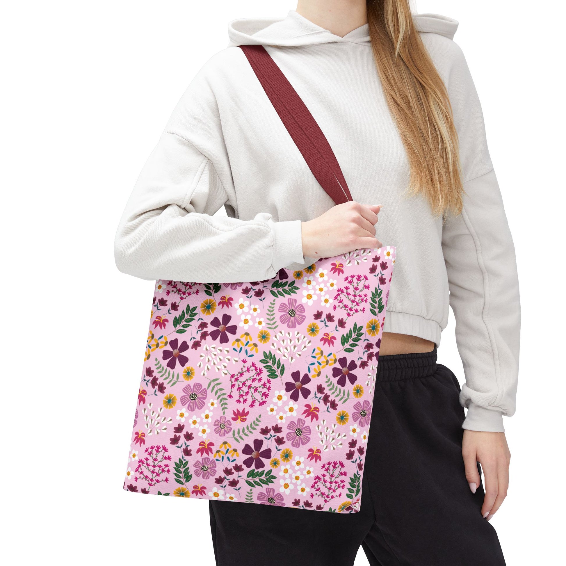 A person carries the Floral Tote Bag, featuring a burgundy strap and a pink background with a vibrant floral print, showcasing its stylish and durable design for versatile everyday use.
