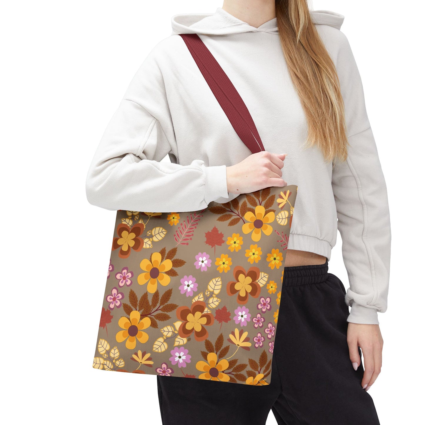 Person wearing loungewear holds the Harvest Brown Bloom Tote Bag, featuring an autumn-inspired floral pattern on a muted brown background, ideal for joyful outings.