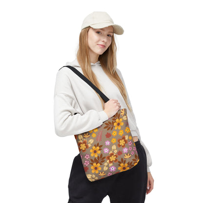 Young woman models the Harvest Brown Bloom Tote Bag with a vibrant floral pattern in autumnal tones. Ideal for joyful, stylish outings, it complements her casual attire, featuring durable 100% polyester construction.