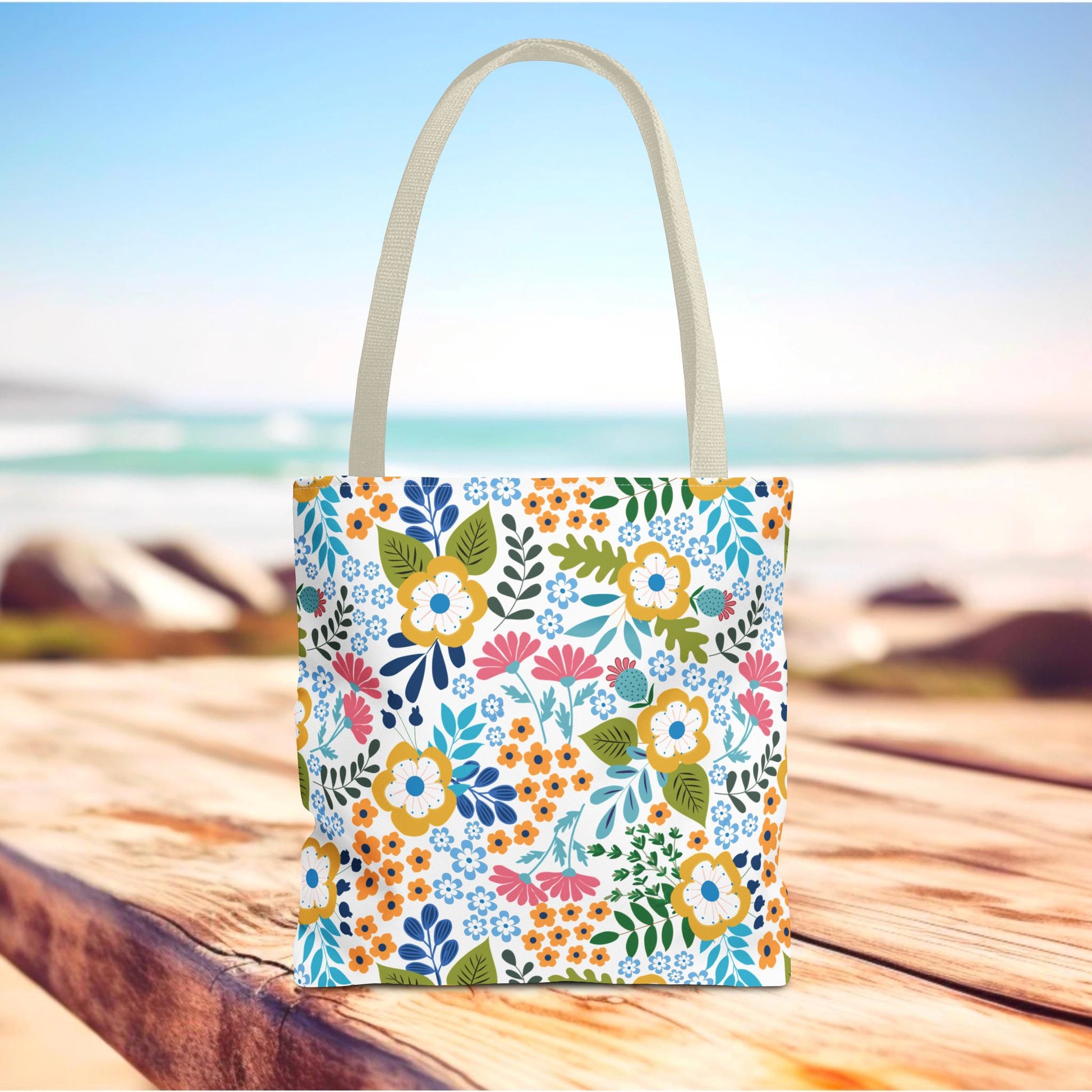 Floral Tote Bag with vibrant blooms and cream handles on a wooden surface, embodying joyful style and practicality for summer outings, by FireBrook Essentials.