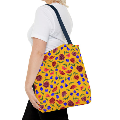 Golden Wildflower Tote Bag with vibrant floral pattern, featuring red and maroon daisies on a mustard-yellow background. Navy blue straps complement the cheerful design, embodying FireBrook Designs' joyful, practical aesthetic.