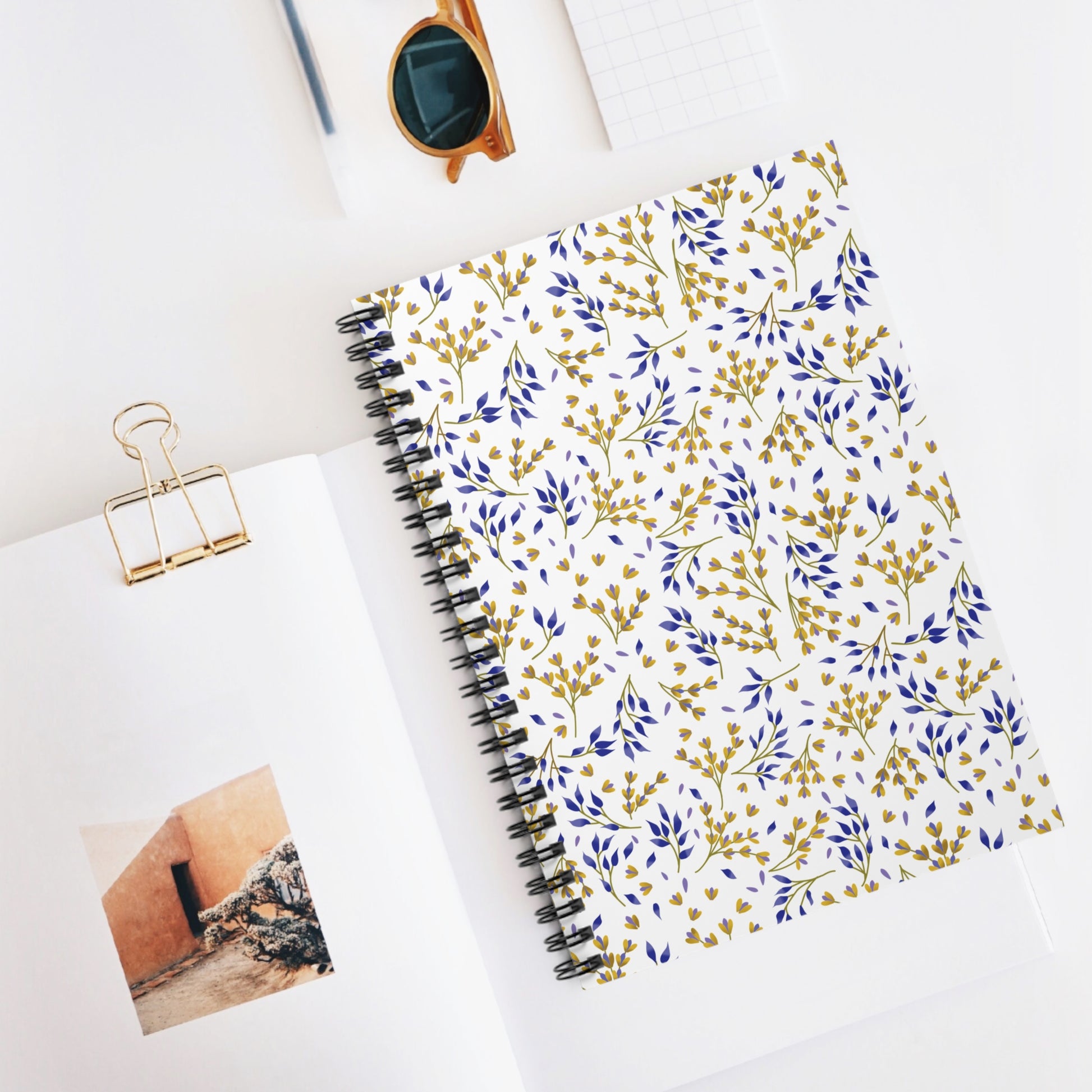 SPIRAL NOTEBOOK, DURABLE COVER, RULED, 6X8 – SPRING BRANCHES, features a blue-and-mustard botanical pattern, centered in a desktop still life with stylish accessories, embodying FireBrook Essentials' uplifting, joyful design ethos.