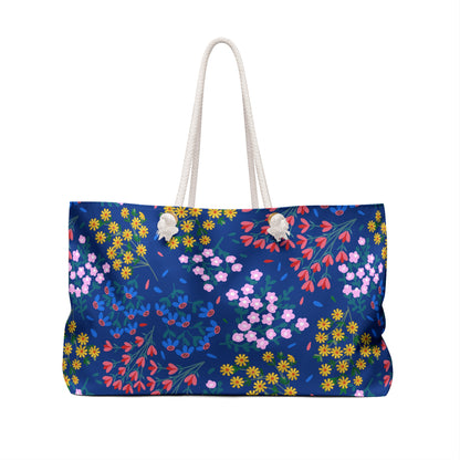 Weekender Bag with a deep blue floral print, featuring white rope handles. Ideal for stylish getaways, it offers a generous size and luxurious cream lining, embodying FireBrook Essentials' blend of comfort and joy.