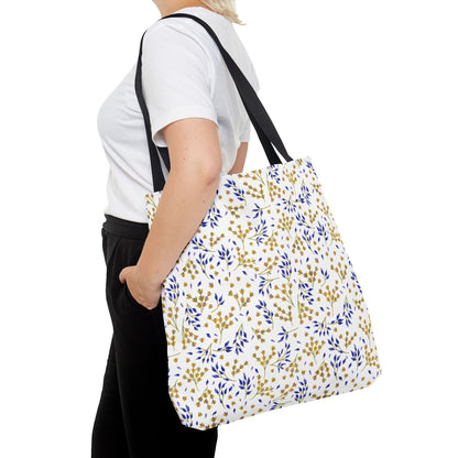 Wild Herb Garden Tote Bag features a white canvas with a delicate botanical pattern in mustard yellow and deep blue, black straps, and a practical design, ideal for vibrant summer outings.