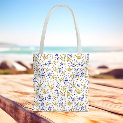 Wild Herb Garden Tote Bag on a wooden surface, featuring a white background with a gold and blue botanical pattern, ideal for summer outings. Sturdy, stylish design complements FireBrook Designs' uplifting product range.