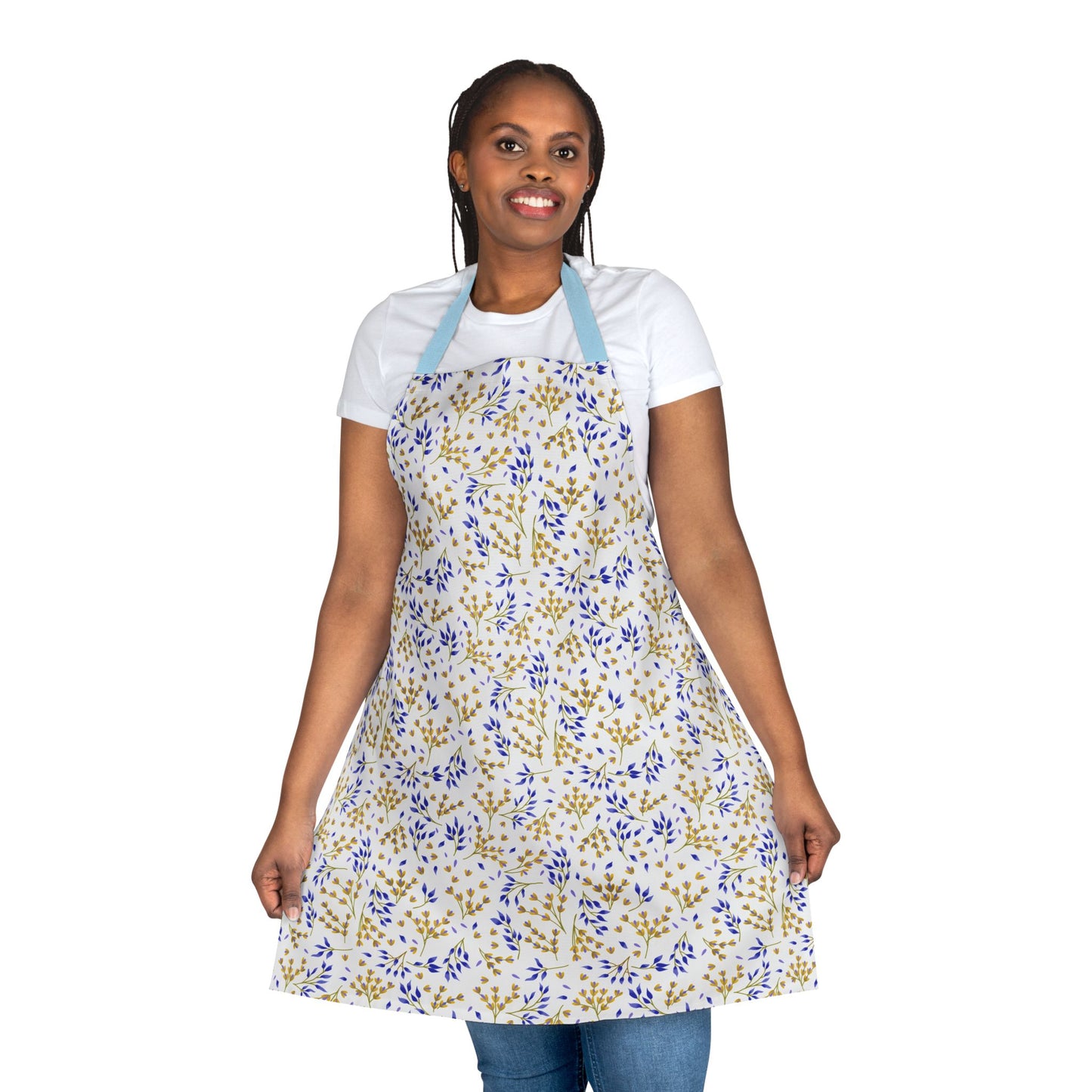 Person wearing a Floral Apron with a small leafy pattern, blue neck straps, smiling, and holding its skirt. Made of polyester canvas, it's designed for comfort and stain-free protection.